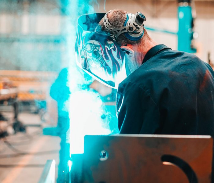 A worker with a welding mask on welding